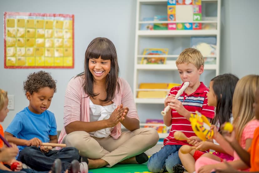 A music therapist doing therapy with a group of children sitting on the floor