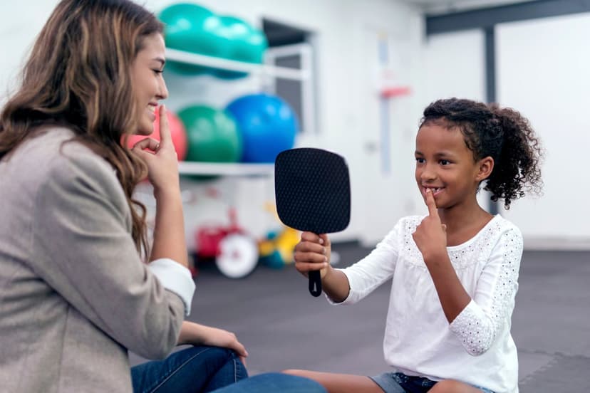 A little girl is practicing saying words with the help of her speech therapist. Better speech intelligibility is a key benefit of speech therapy.