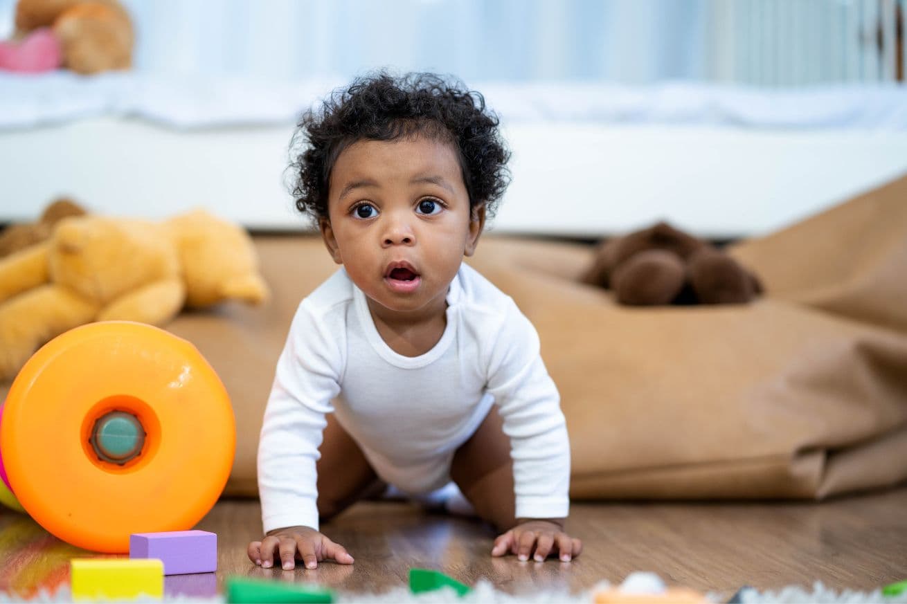 a baby boy crawling next to toys